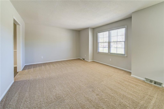 carpeted spare room with visible vents, baseboards, and a textured ceiling