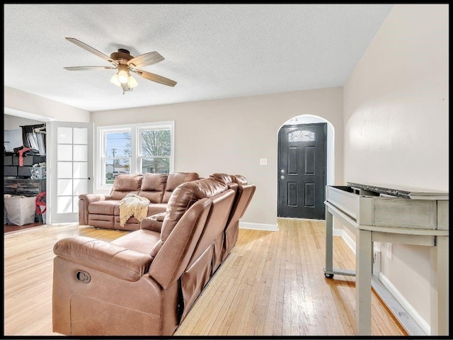 165 S Miami Ave, Marshall, MO 65340 - living area featuring arched walkways, light wood-style floors, ceiling fan, baseboards, and a textured ceiling