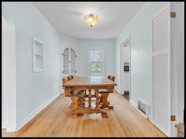 165 S Miami Ave, Marshall, MO 65340 - dining space with arched walkways, visible vents, light wood-style floors, and baseboards
