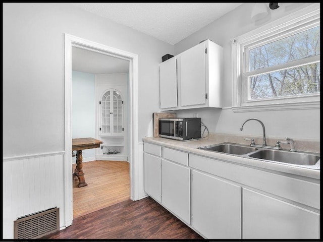 165 S Miami Ave, Marshall, MO 65340 - kitchen featuring stainless steel microwave, light countertops, a sink, white cabinetry, and dark wood-type flooring