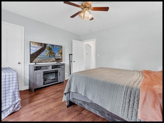 165 S Miami Ave, Marshall, MO 65340 - bedroom featuring a fireplace, wood finished floors, ceiling fan, and arched walkways