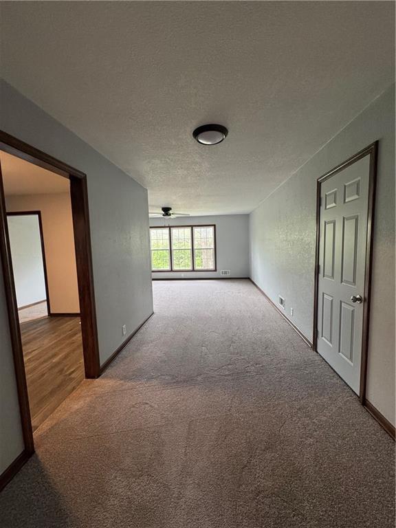 616 Prospect St, Excelsior Springs, MO 64024 - carpeted empty room featuring a textured ceiling and baseboards