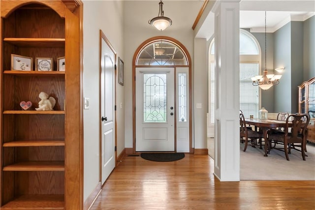 foyer entrance with baseboards, an inviting chandelier, and wood finished floors
