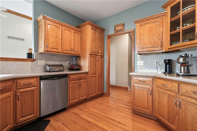 kitchen featuring stainless steel dishwasher, light wood-style floors, light countertops, and visible vents