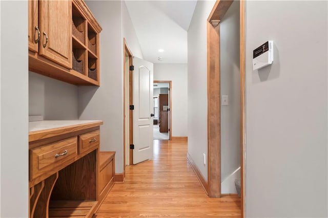 corridor with light wood finished floors and baseboards