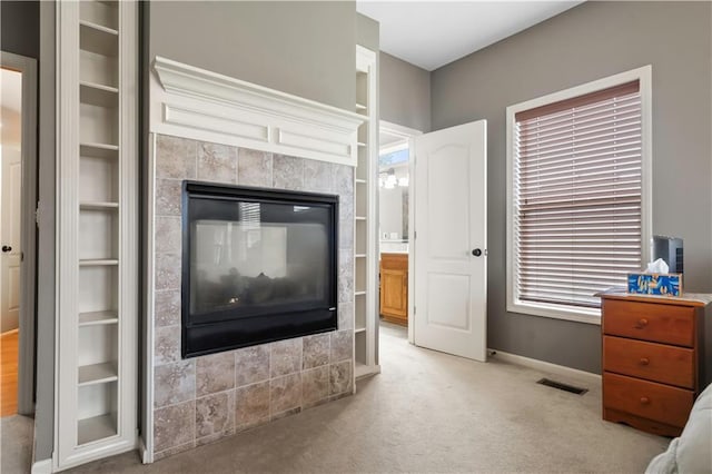 interior space featuring a tile fireplace, baseboards, visible vents, and built in features