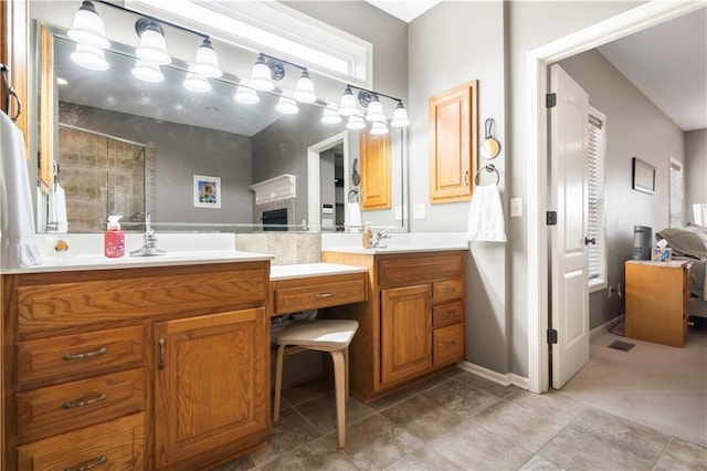 bathroom with baseboards, double vanity, a stall shower, a fireplace, and a sink