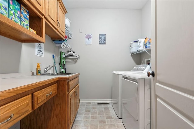 washroom with a sink, baseboards, cabinet space, and separate washer and dryer