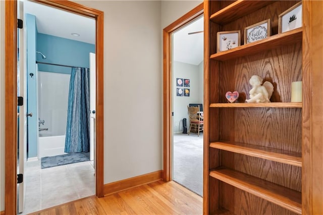 corridor featuring baseboards and wood finished floors