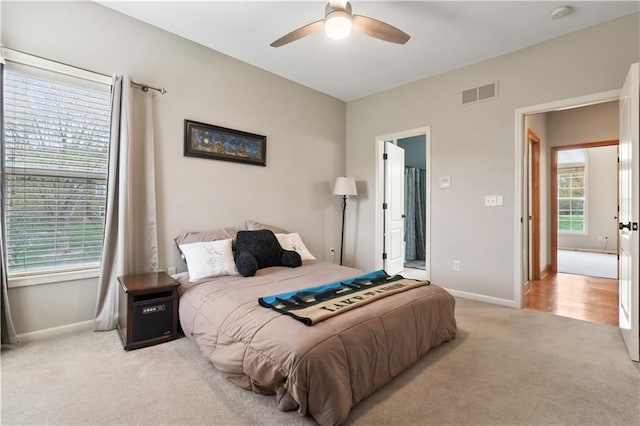 bedroom with baseboards, light carpet, ensuite bathroom, a ceiling fan, and visible vents