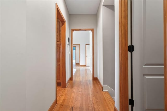corridor featuring light wood-type flooring and baseboards