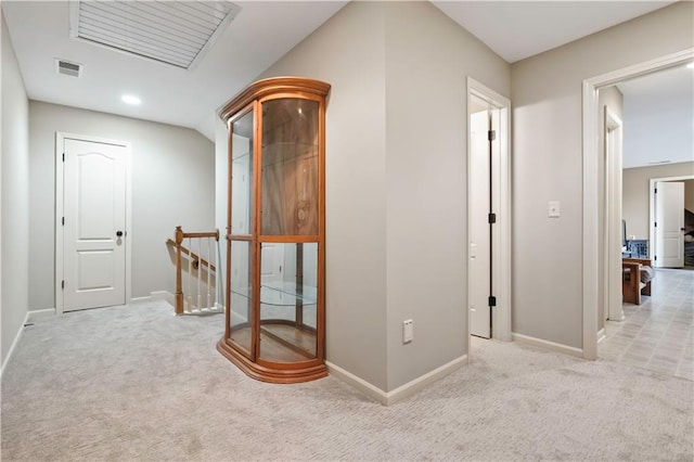 hall with visible vents, baseboards, an upstairs landing, and carpet floors