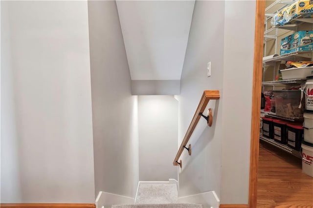 staircase with wood finished floors and lofted ceiling