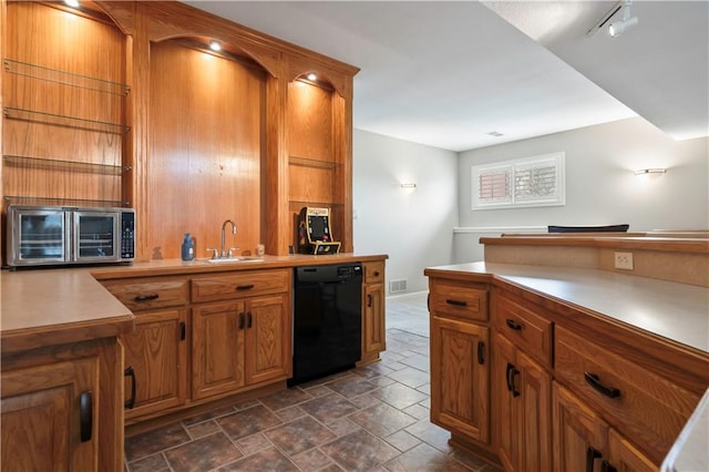 kitchen with light countertops, brown cabinets, stone finish flooring, dishwasher, and a sink
