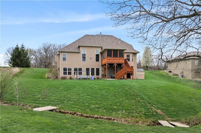 rear view of house featuring stucco siding, a lawn, stairway, a sunroom, and a shingled roof