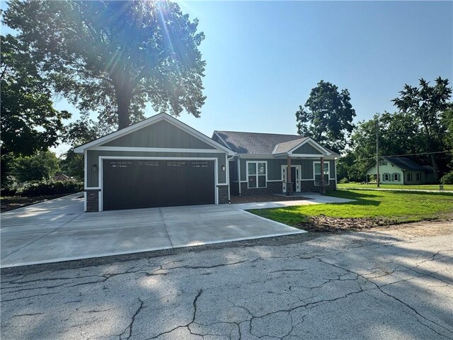 101 N Maple St, Butler, MO 64730 - ranch-style home with a garage, driveway, a front lawn, and board and batten siding