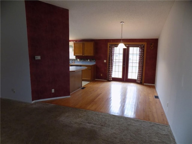 518 S Pine, Ottawa, KS 66067 - kitchen featuring pendant lighting, brown cabinetry, a textured ceiling, light colored carpet, and light wood finished floors