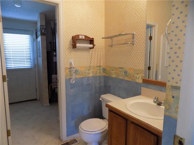 518 S Pine, Ottawa, KS 66067 - bathroom with vanity, wallpapered walls, toilet, gas water heater, and visible vents