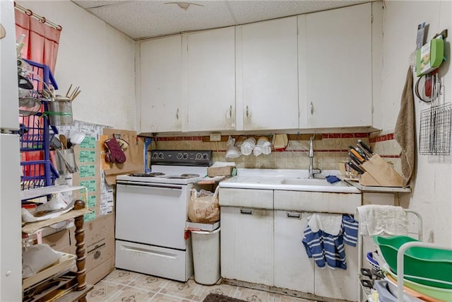 kitchen with white electric range, a sink, and white cabinets
