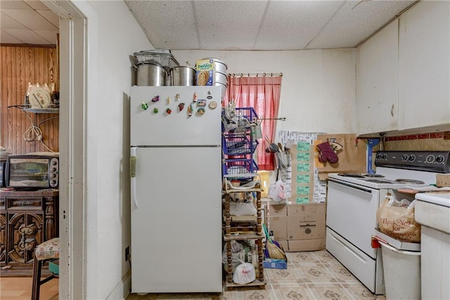 kitchen with a paneled ceiling, wood walls, a toaster, and white appliances