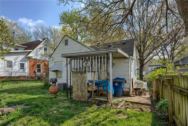 rear view of house with roof with shingles, a fenced backyard, and a lawn