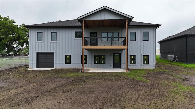 284 SW 1311th Rd, Holden, MO 64040 - rear view of house with a balcony, board and batten siding, an attached garage, central AC unit, and a patio area