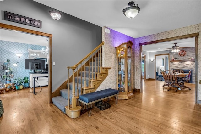 stairs with baseboards, wallpapered walls, wood finished floors, and an accent wall