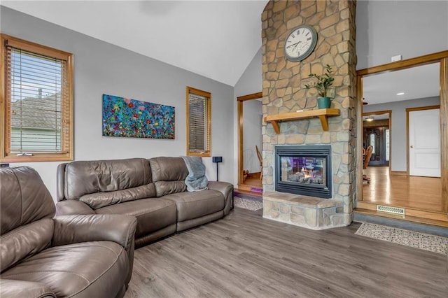 living room with high vaulted ceiling, a fireplace, wood finished floors, and visible vents