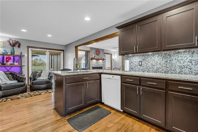 kitchen with a sink, dark brown cabinets, open floor plan, and dishwasher