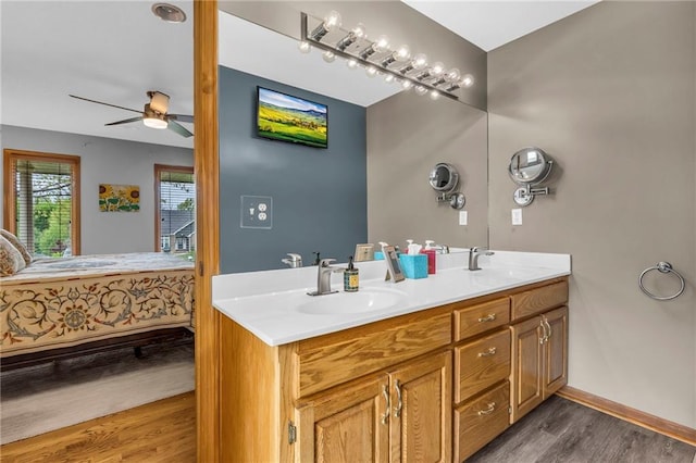 ensuite bathroom featuring connected bathroom, ceiling fan, a sink, and wood finished floors