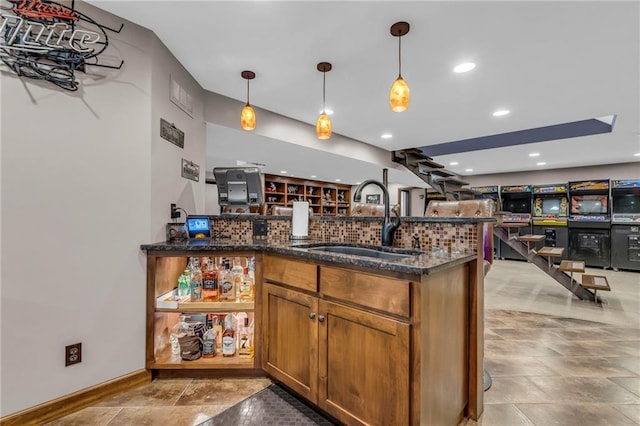 kitchen featuring a sink, dark stone countertops, brown cabinets, and pendant lighting
