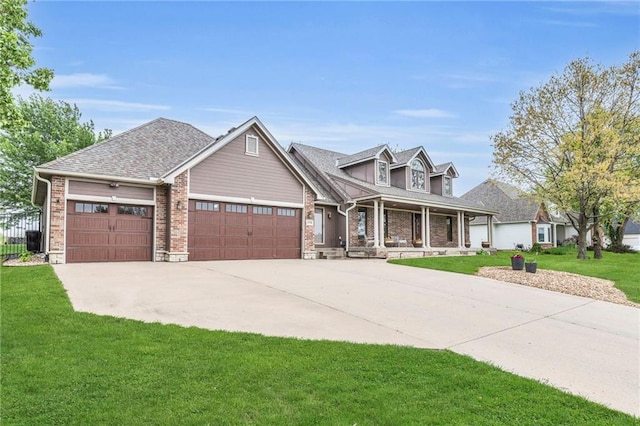 view of front of property featuring a porch, a garage, a front lawn, and driveway