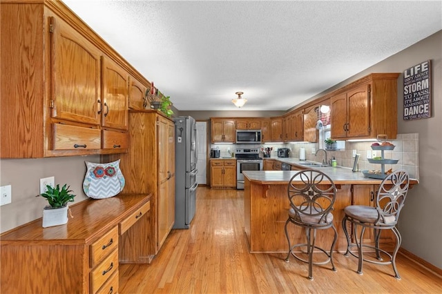 808 S Mohican Dr, Independence, MO 64056 - kitchen featuring brown cabinetry, a peninsula, appliances with stainless steel finishes, and a sink