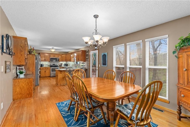 808 S Mohican Dr, Independence, MO 64056 - dining space with light wood-style floors, a textured ceiling, visible vents, a chandelier, and baseboards