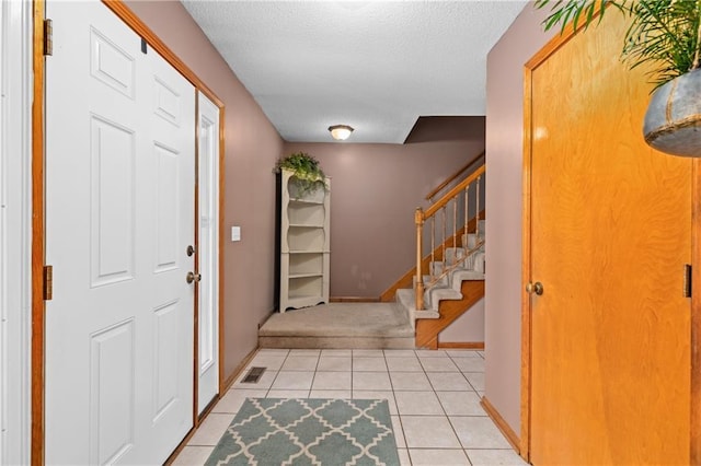 808 S Mohican Dr, Independence, MO 64056 - foyer entrance featuring a textured ceiling, light tile patterned flooring, visible vents, and stairs