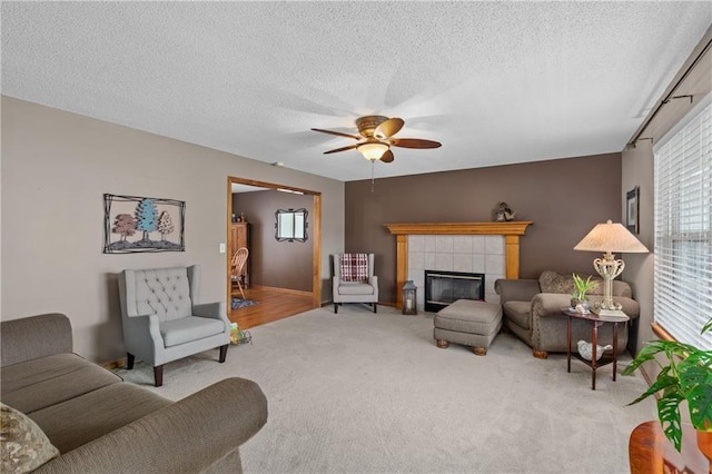 808 S Mohican Dr, Independence, MO 64056 - living room featuring a tiled fireplace, carpet flooring, a textured ceiling, and a ceiling fan