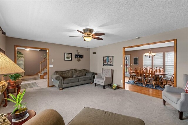 808 S Mohican Dr, Independence, MO 64056 - living area featuring ceiling fan with notable chandelier, a textured ceiling, carpet, and stairs