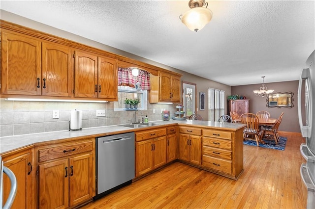 808 S Mohican Dr, Independence, MO 64056 - kitchen featuring brown cabinetry, a peninsula, appliances with stainless steel finishes, and a sink