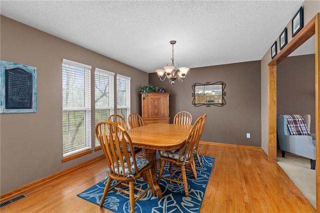 808 S Mohican Dr, Independence, MO 64056 - dining room with visible vents, baseboards, an inviting chandelier, a textured ceiling, and light wood-style flooring