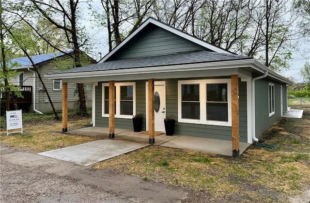 bungalow-style home featuring a porch and roof with shingles