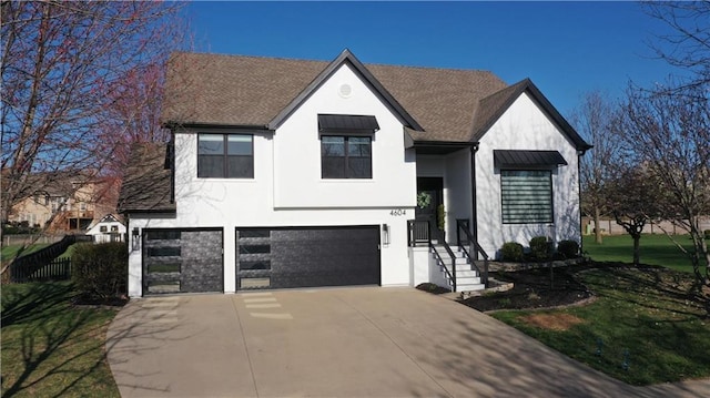 view of front facade featuring a garage, fence, stucco siding, a front lawn, and driveway