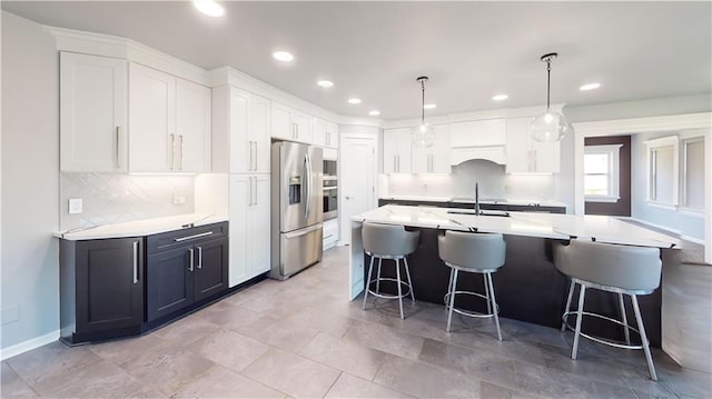 kitchen featuring white cabinets, a sink, appliances with stainless steel finishes, recessed lighting, and a breakfast bar area