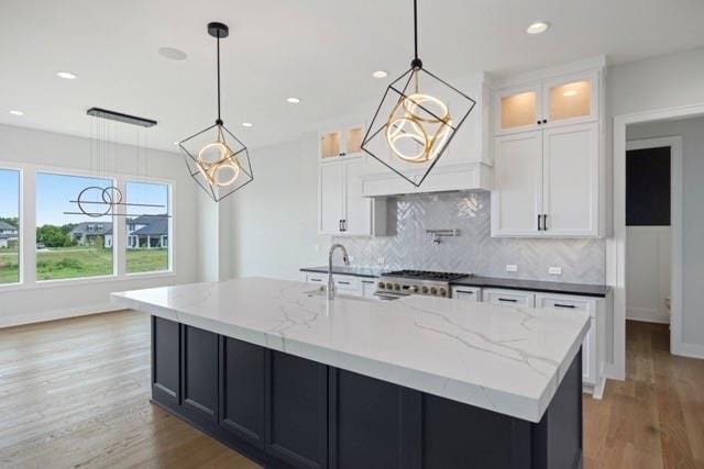 17216 Goddard St, Overland Park, KS 66221 - kitchen with light wood-style floors, decorative backsplash, stove, and an island with sink