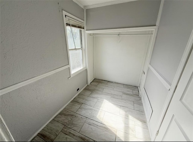 2907 E 61st St, Kansas City, MO 64130 - unfurnished bedroom featuring light marble finish floors, a textured wall, crown molding, and a closet