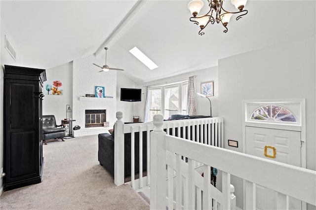 hallway featuring visible vents, an inviting chandelier, light carpet, vaulted ceiling with skylight, and an upstairs landing