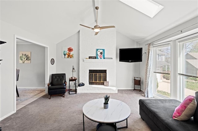 carpeted living room featuring baseboards, a ceiling fan, a brick fireplace, and vaulted ceiling with skylight