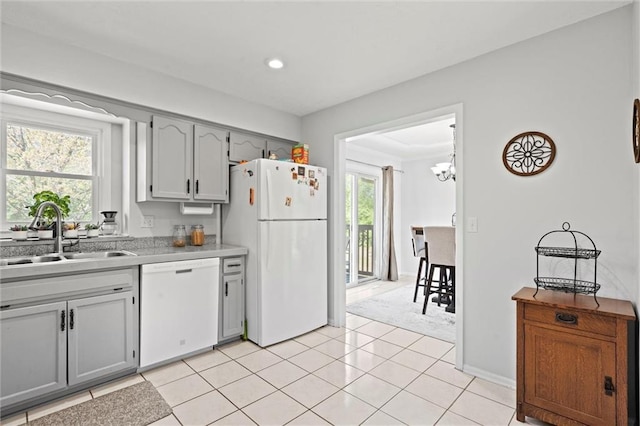 kitchen with gray cabinets, a sink, light countertops, white appliances, and light tile patterned flooring