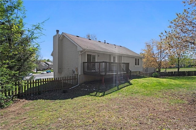 rear view of house featuring a fenced backyard, a wooden deck, a chimney, and a lawn