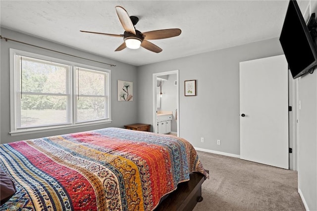 carpeted bedroom with baseboards, multiple windows, a ceiling fan, and ensuite bath