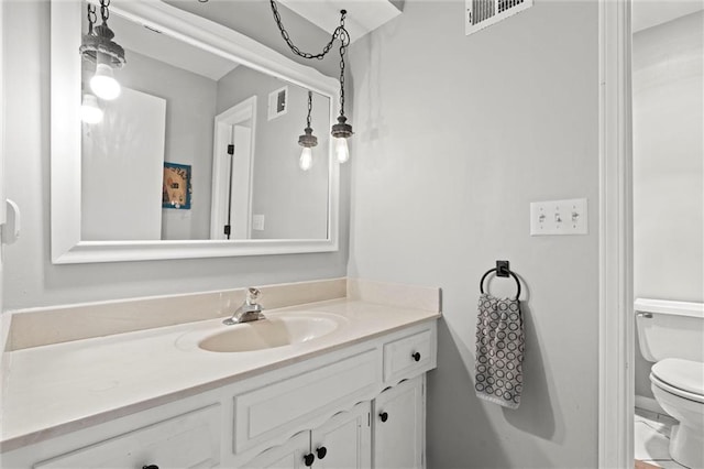 bathroom with vanity, toilet, and visible vents
